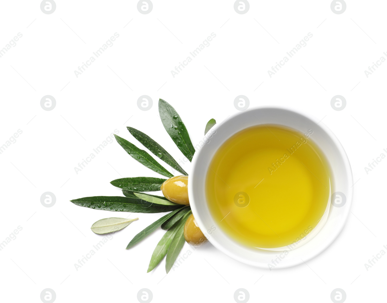 Photo of Little bowl with oil, ripe olives and leaves on white background