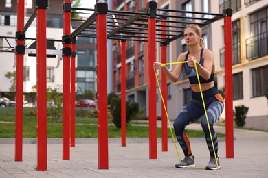Athletic woman doing exercise with fitness elastic band at outdoor gym