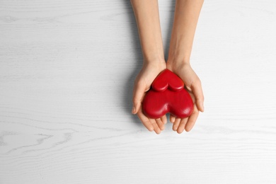 Woman holding decorative hearts on white wooden background, top view. Space for text