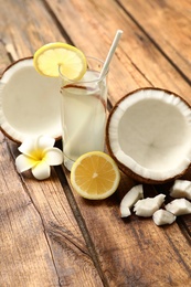 Photo of Composition with glass of coconut water and lemon on wooden table