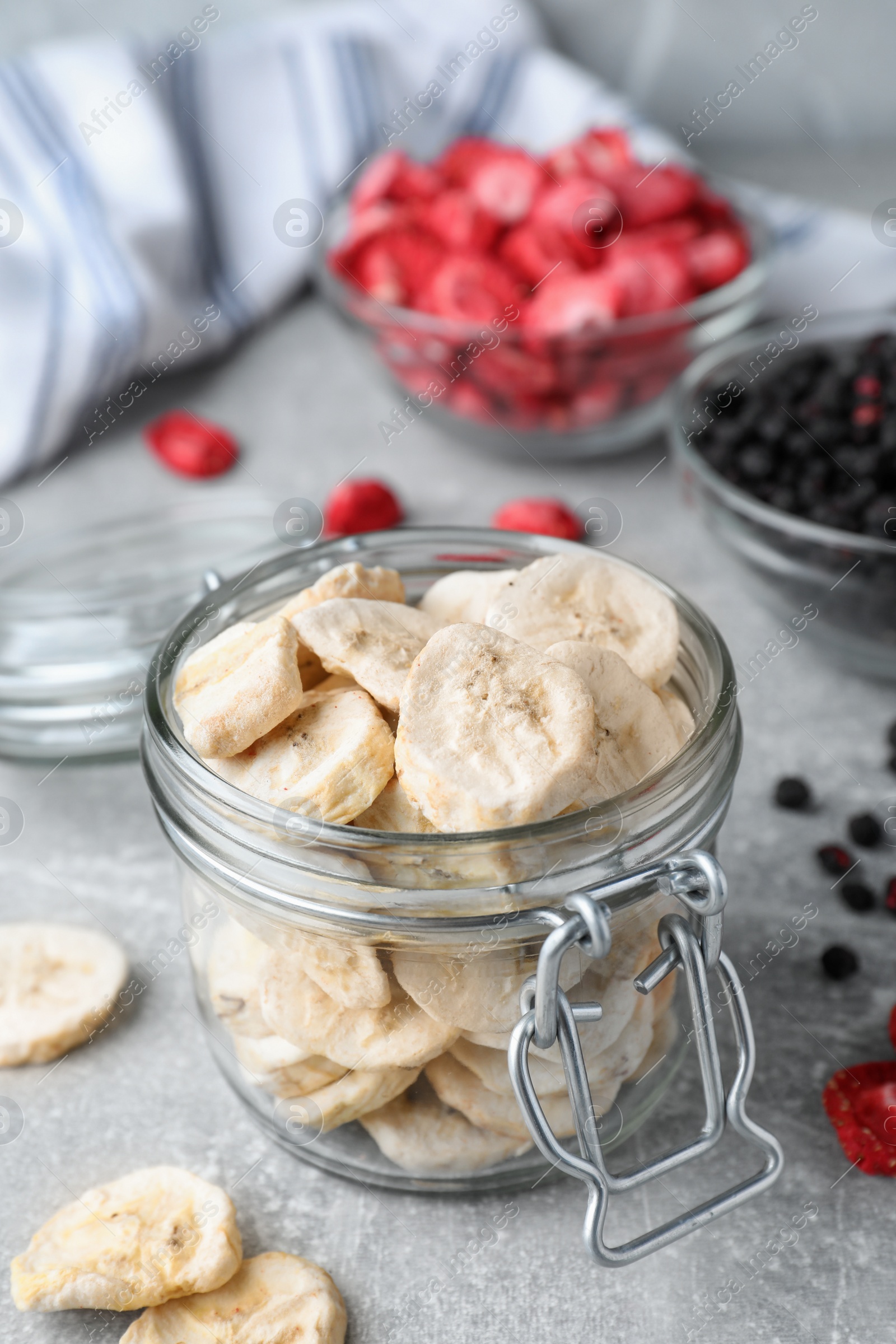 Photo of Glass jar of freeze dried banana pieces on light grey table