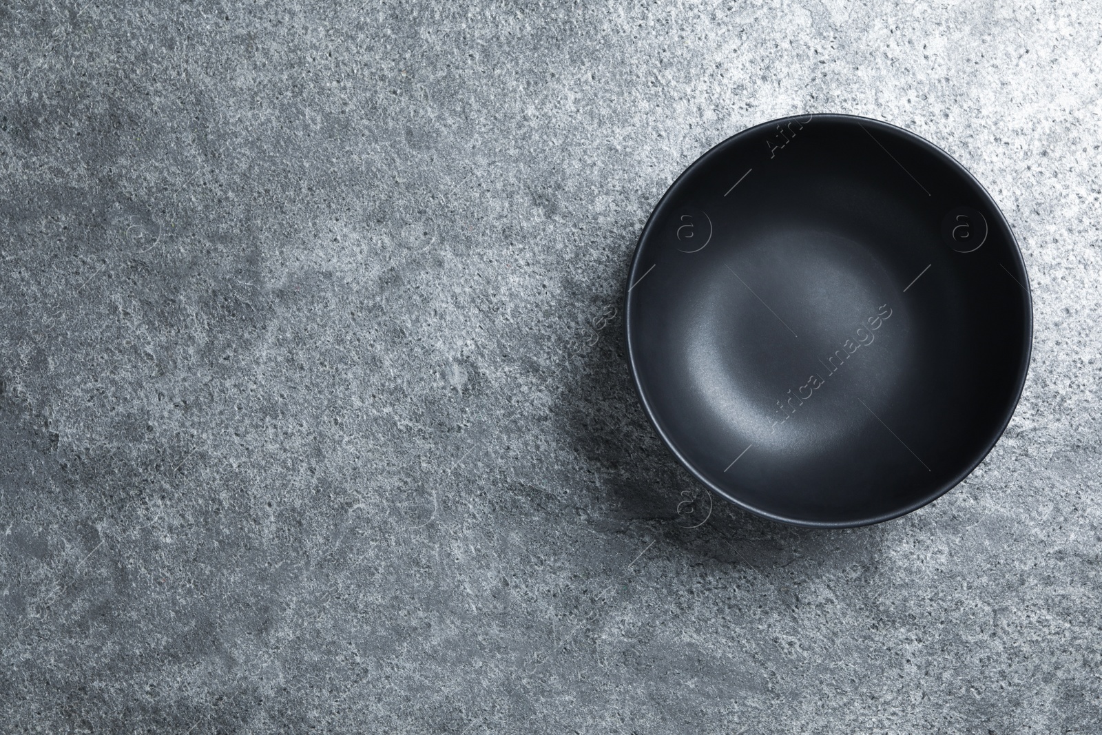 Photo of Empty clean ceramic bowl on grey table, top view. Space for text