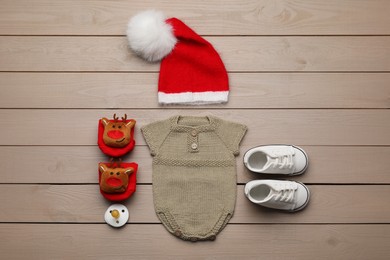 Photo of Set of baby clothes for Christmas photoshoot on wooden background, flat lay