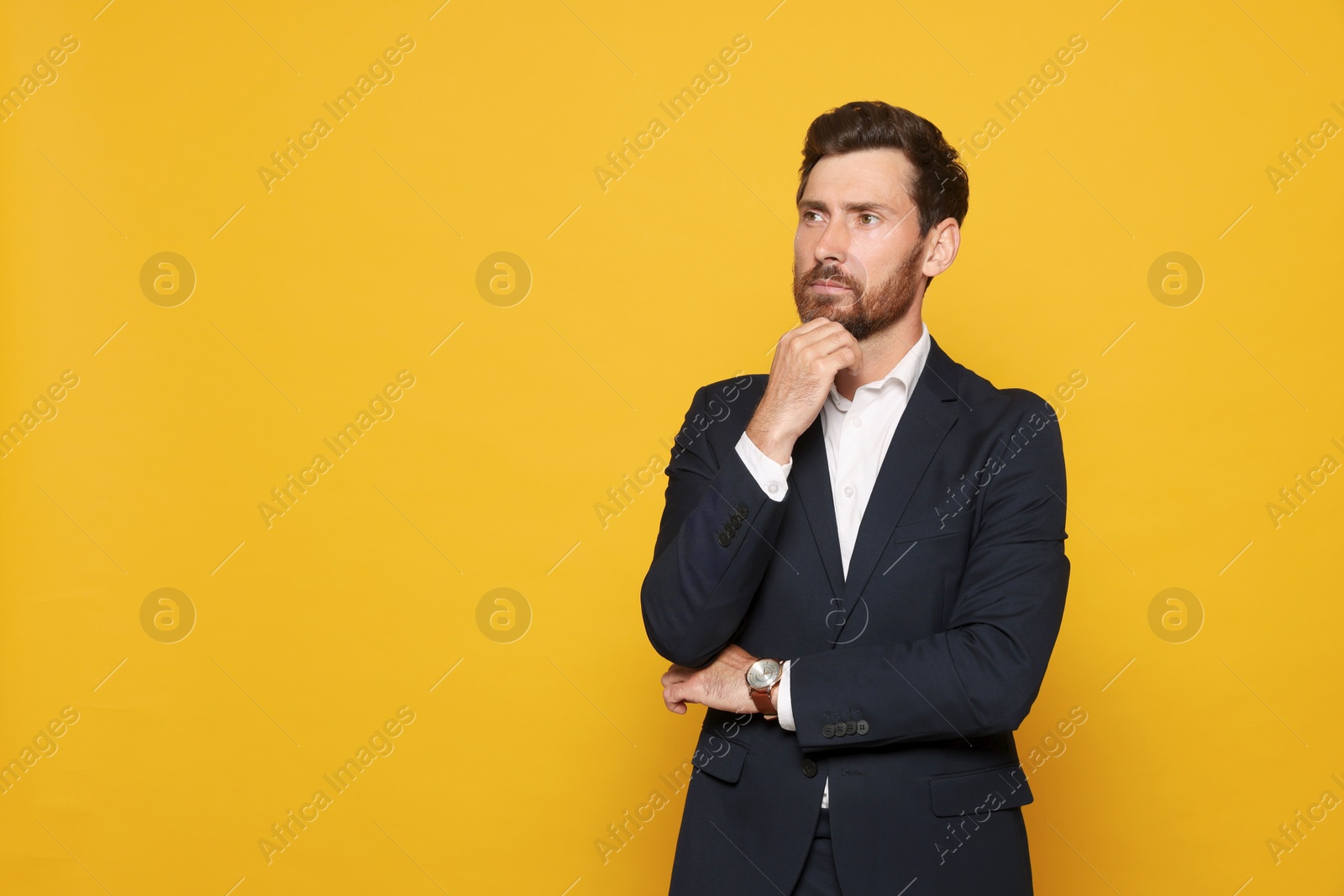 Photo of Pensive bearded man in suit looking away on orange background. Space for text