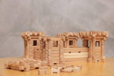 Photo of Wooden fortress and building blocks on table against grey background. Children's toy