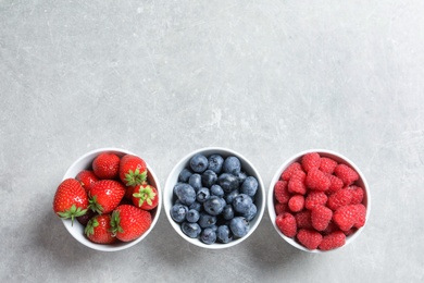 Bowls with raspberries, strawberries and blueberries on table, top view