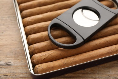 Photo of Box of cigars and guillotine cutter on wooden table, closeup