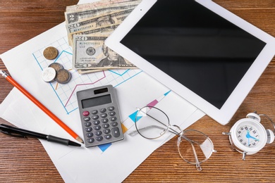 Composition with tablet, calculator and money on wooden table. Pension planning