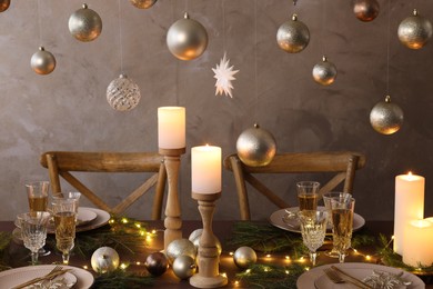 Photo of Christmas table setting with burning candles and festive decor