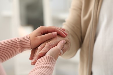 Photo of Trust and support. Woman with her dad joining hands indoors, closeup