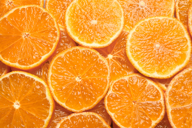 Photo of Slices of fresh ripe tangerines as background, top view. Citrus fruit