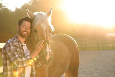 Photo of Man with adorable horse outdoors on sunny day, space for text. Lovely domesticated pet