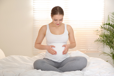 Photo of Young pregnant woman on bed at home