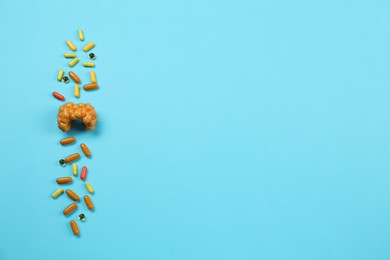 Endocrinology. Capsules and model of thyroid gland on light blue background, top view. Space for text