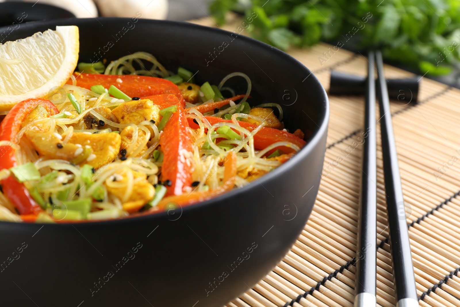 Photo of Stir-fry. Delicious cooked noodles with chicken and vegetables in bowl served on table, closeup