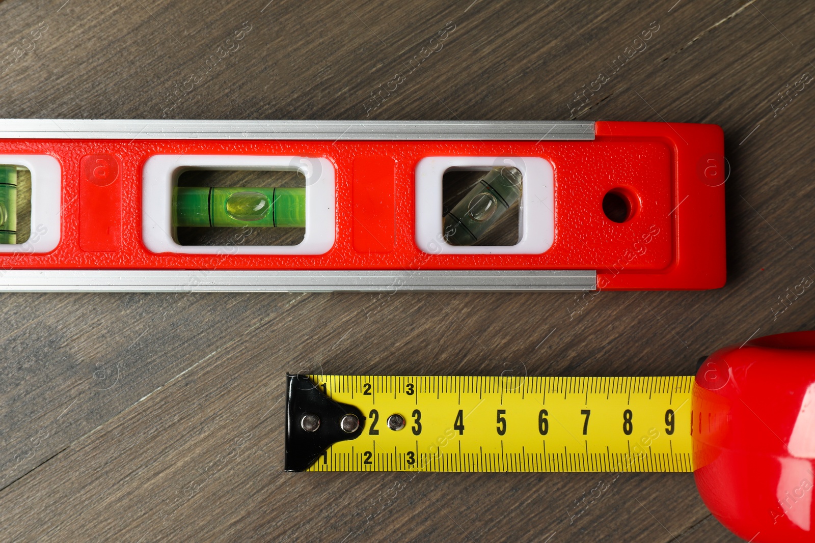 Photo of Building level and tape measure on wooden table, top view