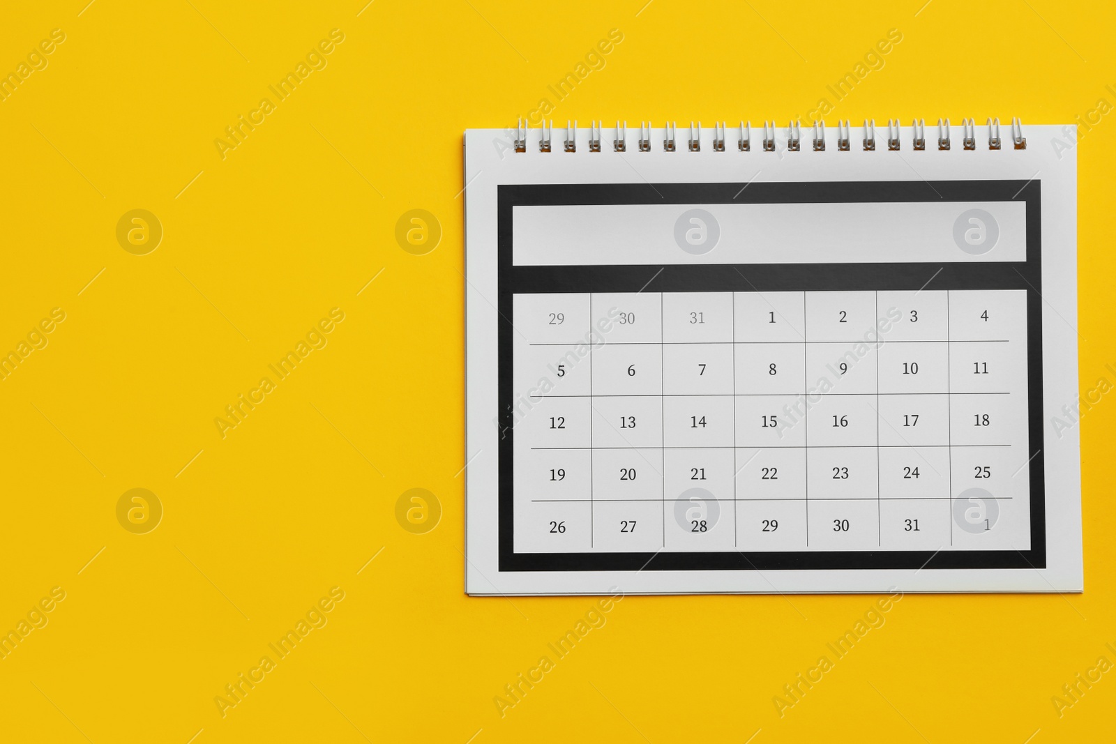 Photo of Paper calendar on yellow background, top view. Space for text