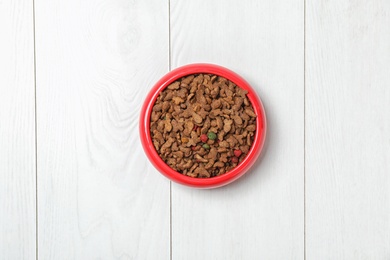 Photo of Bowl with food for cat or dog on wooden background. Pet care