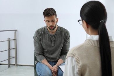 Photo of Psychotherapist working with drug addicted man indoors