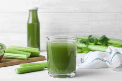 Glass of fresh celery juice on white wooden table