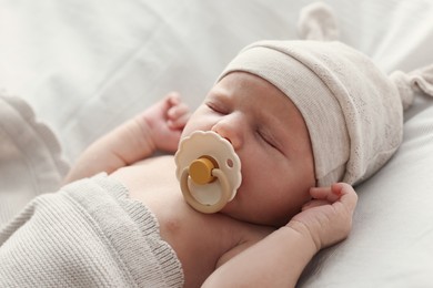 Photo of Adorable little baby with pacifier sleeping in bed, closeup