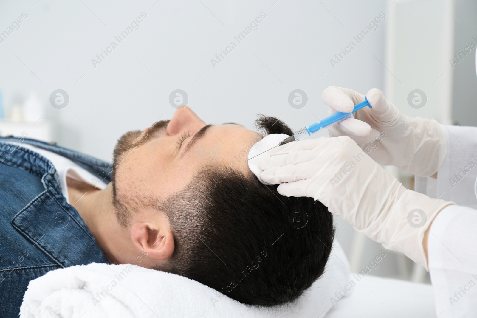 Photo of Man with hair loss problem receiving injection in salon