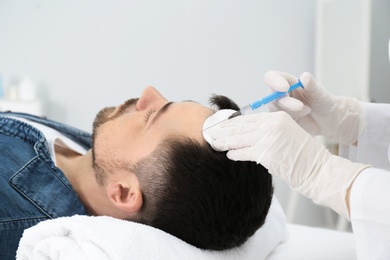 Photo of Man with hair loss problem receiving injection in salon