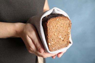 Photo of Baker holding cut bread on color background, closeup