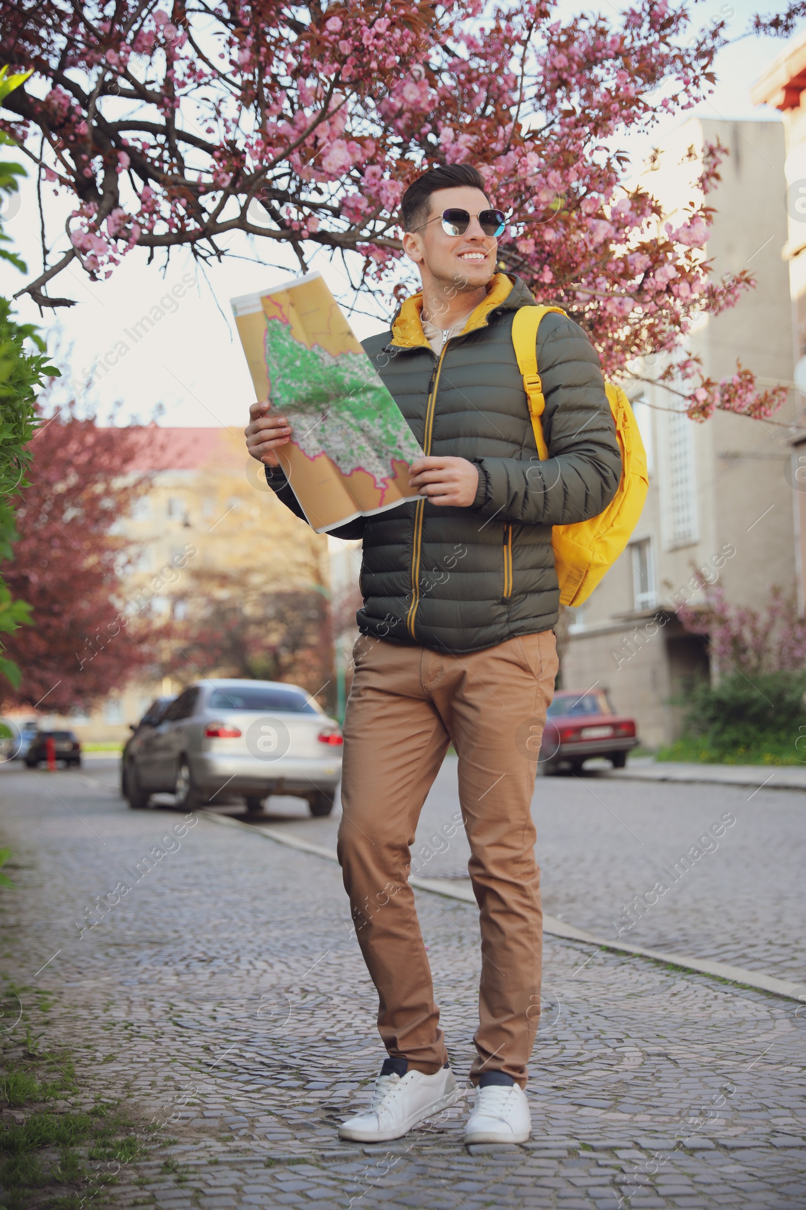 Photo of Happy male tourist with map on city street