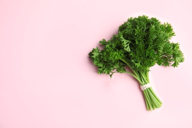 Photo of Bunch of fresh green parsley on pink background, top view. Space for text
