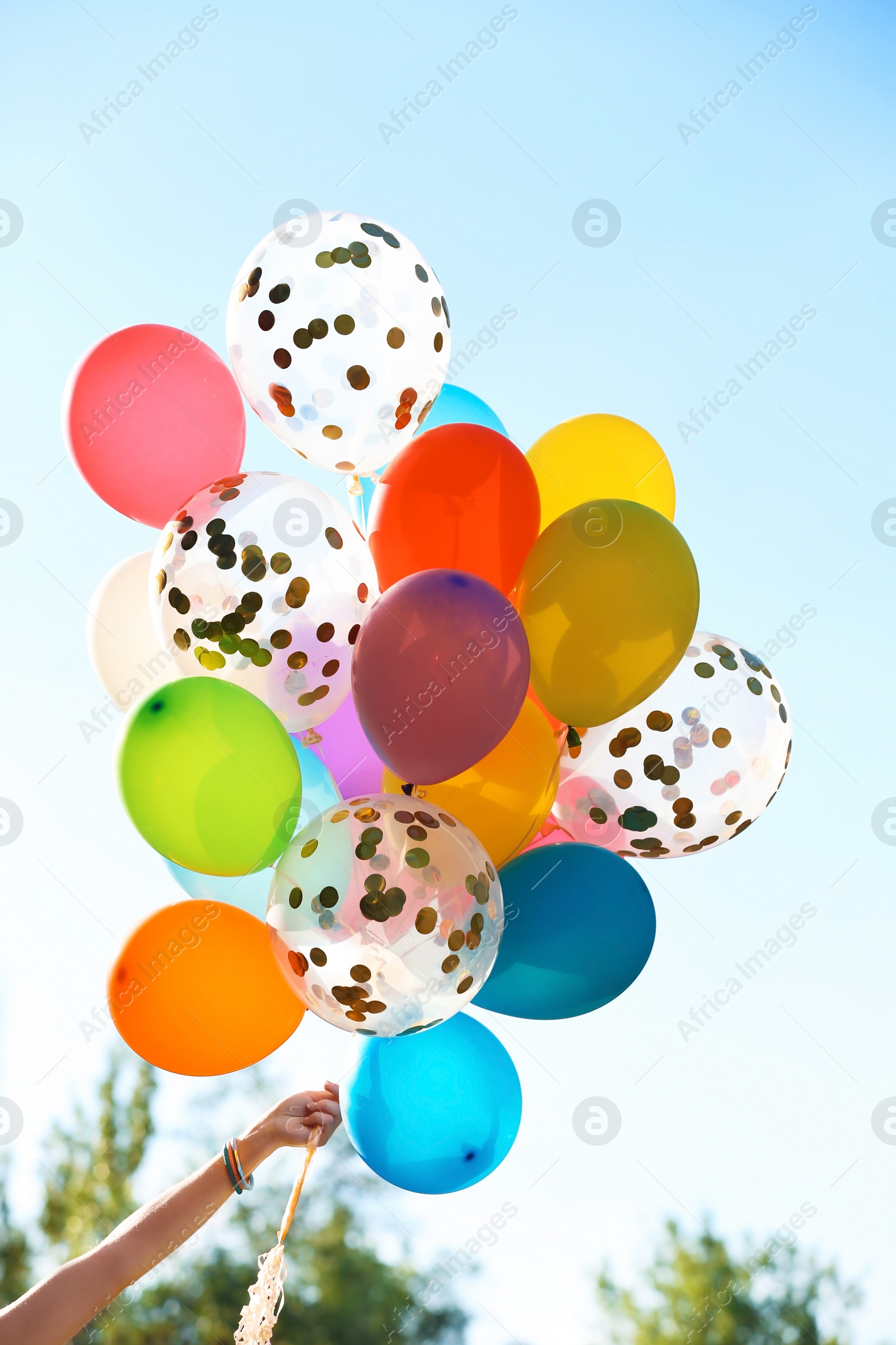 Photo of Young woman with colorful balloons outdoors on sunny day