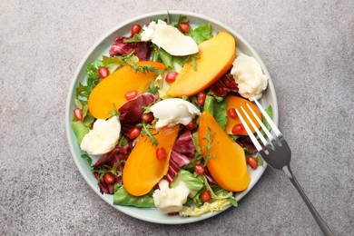 Delicious persimmon salad with cheese and pomegranate served on grey table, top view