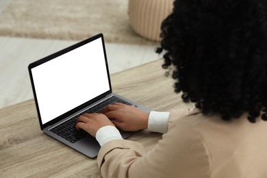 Woman using laptop at wooden desk indoors, closeup