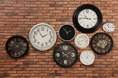 Photo of Collection of clocks hanging on red brick wall