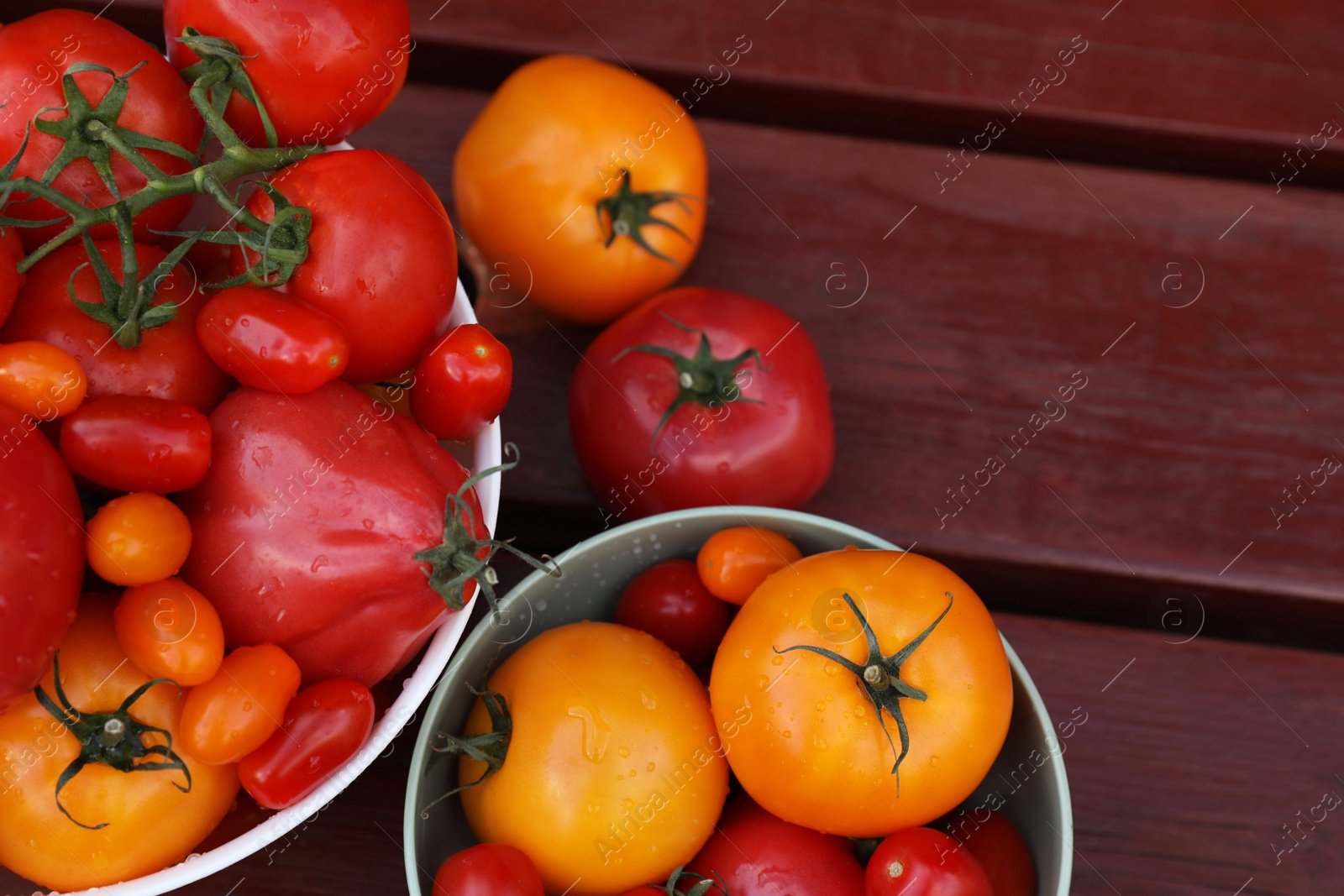 Photo of Bowls with fresh tomatoes on wooden table, flat lay. Space for text