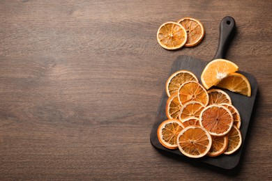 Dry and fresh orange slices on wooden table, flat lay. Space for text