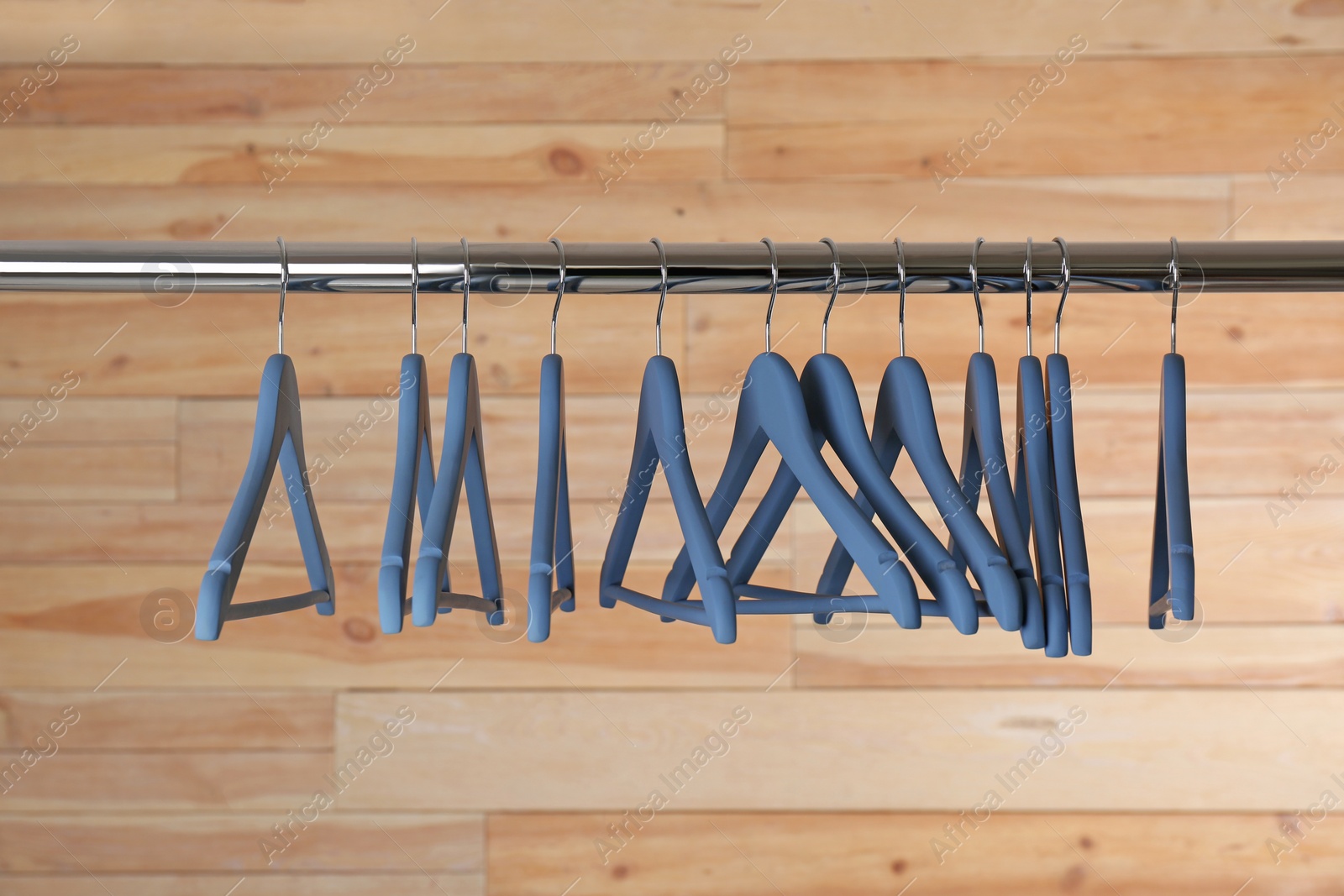 Photo of Metal rack with clothes hangers on wooden background