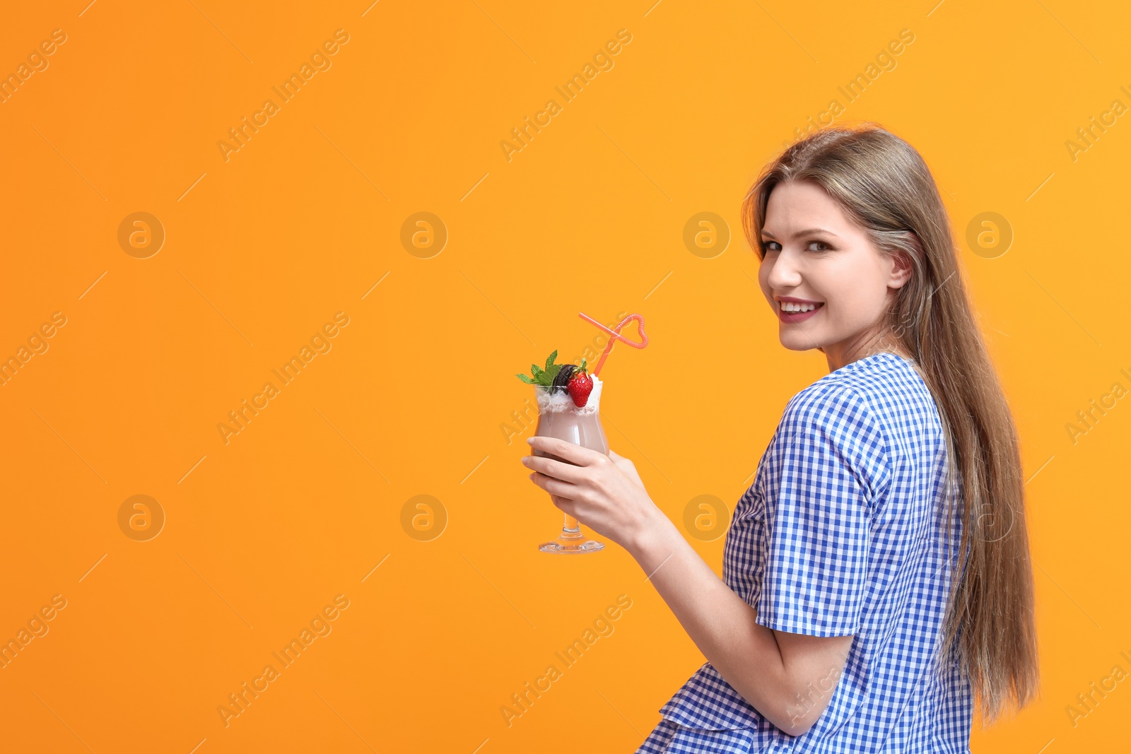 Photo of Young woman with glass of delicious milk shake on color background