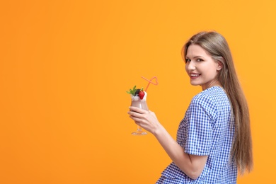 Photo of Young woman with glass of delicious milk shake on color background