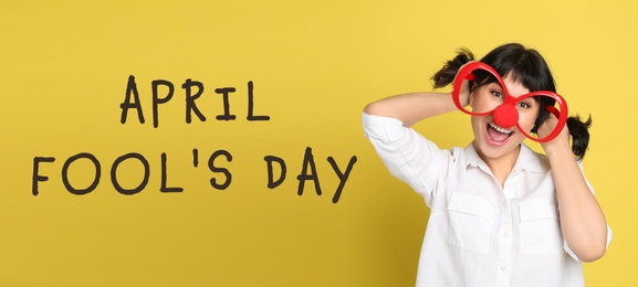 Funny woman with large glasses and clown nose on yellow background, banner design. April fool's day