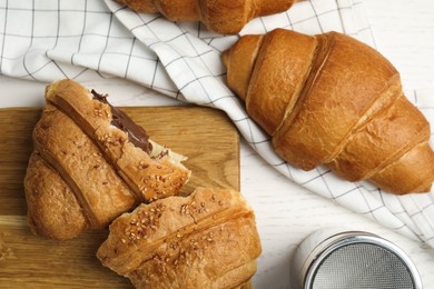 Tasty croissants with chocolate on white wooden table, flat lay