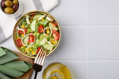 Photo of Bowl of tasty salad with leek, tomatoes and cucumbers on white tiled table, flat lay. Space for text
