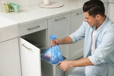 Photo of Man taking garbage bag out of bin at home
