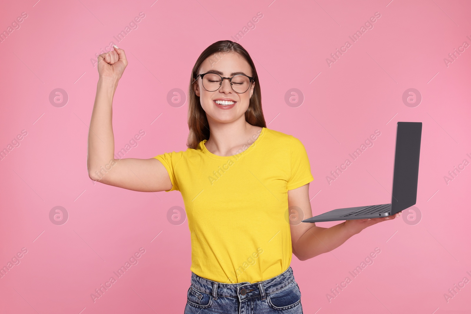 Photo of Happy woman in glasses with laptop on pink background