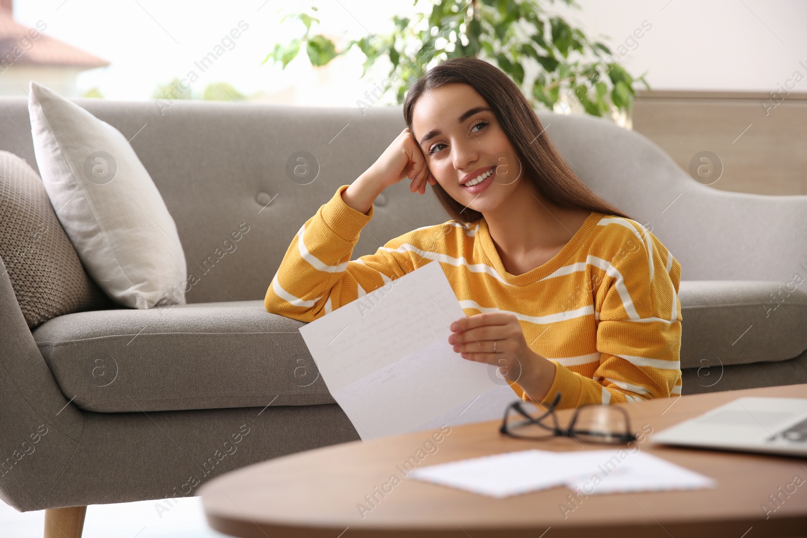 Photo of Young woman reading paper letter at home