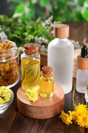 Bottles of essential oils and different herbs on wooden table