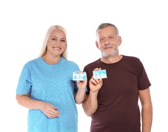 Happy mature couple with driving licenses on white background