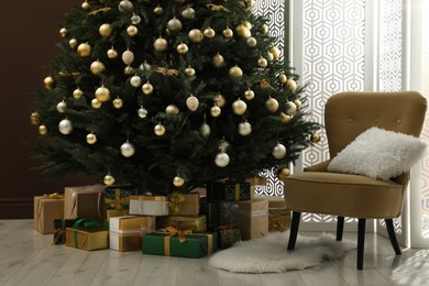 Beautifully decorated Christmas tree and many gift boxes near brown wall in room