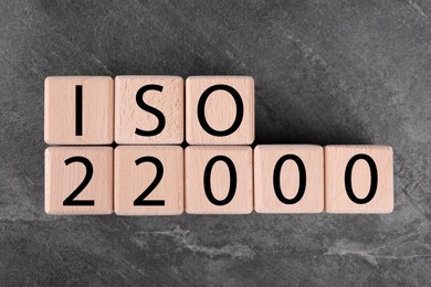 Photo of International Organization for Standardization. Cubes with abbreviation ISO 22000 on gray textured table, top view