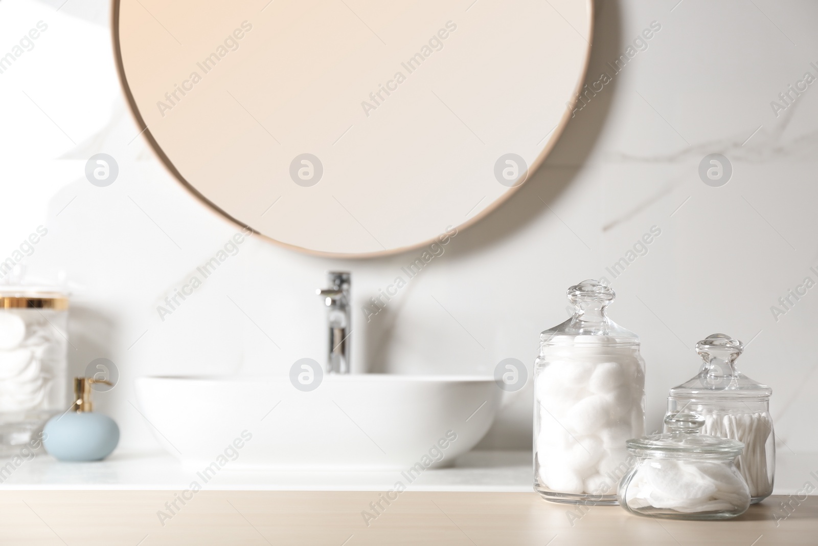 Photo of Cotton balls, swabs and pads on wooden table in bathroom